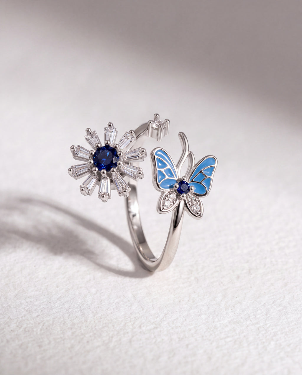 Butterfly and Flower Serenara Anxiety Ring standing upright on white textured watercolor paper, soft shadow