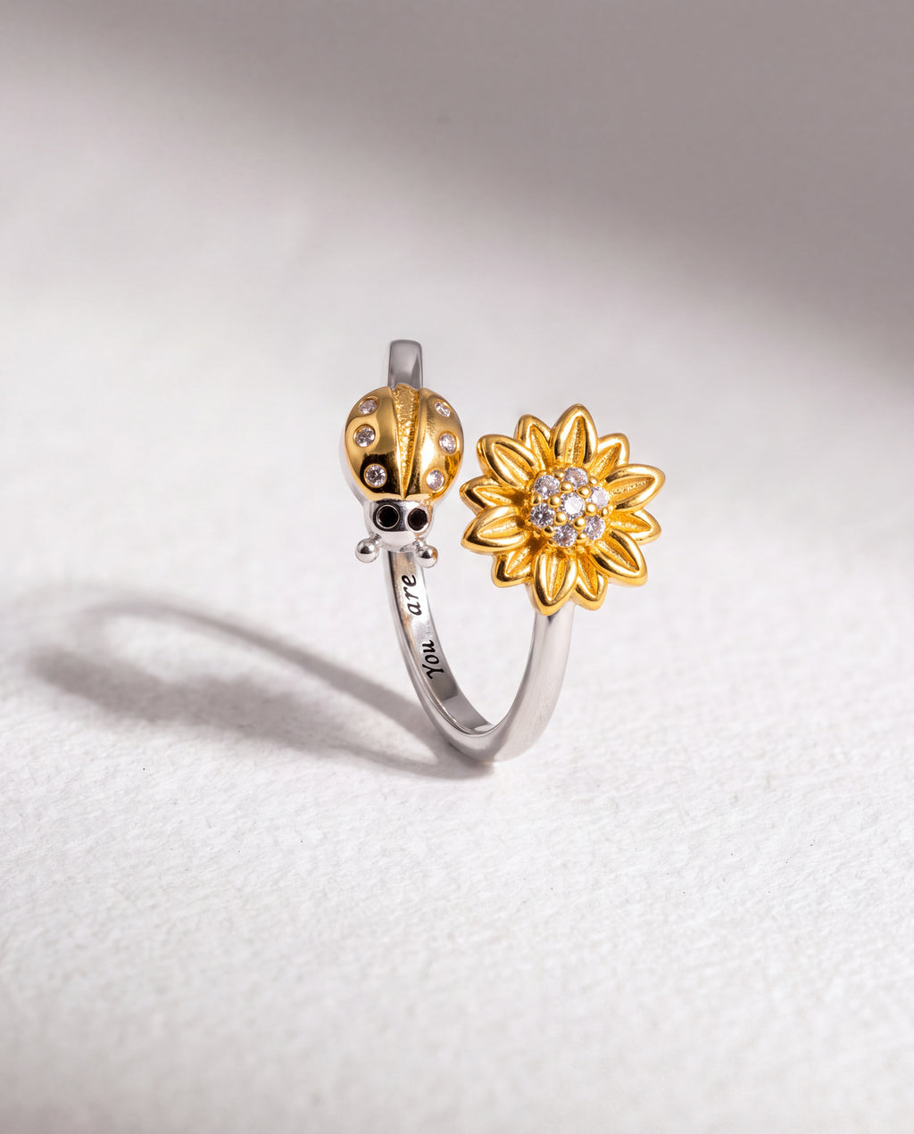 Ladybug Serenara Anxiety Ring standing upright on white textured watercolor paper, soft shadow