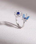 Butterfly and Flower Serenara Anxiety Ring standing upright on white textured watercolor paper